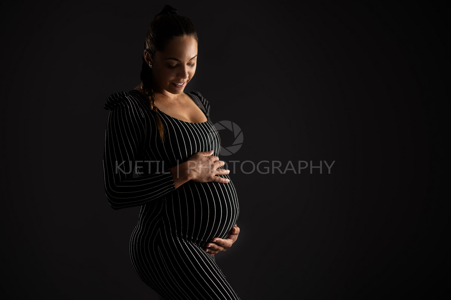Smiling Pregnant Woman in Striped Dress with Black Background