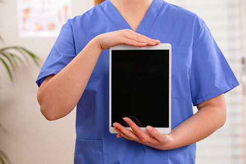 Adult female doctor or nurse show a digital image or report on a tablet