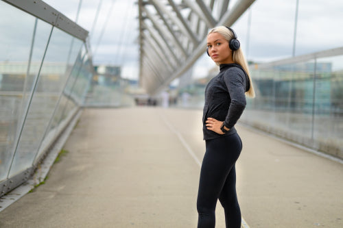 Woman in Black Workout Outfit Standing At Modern Bridge In City