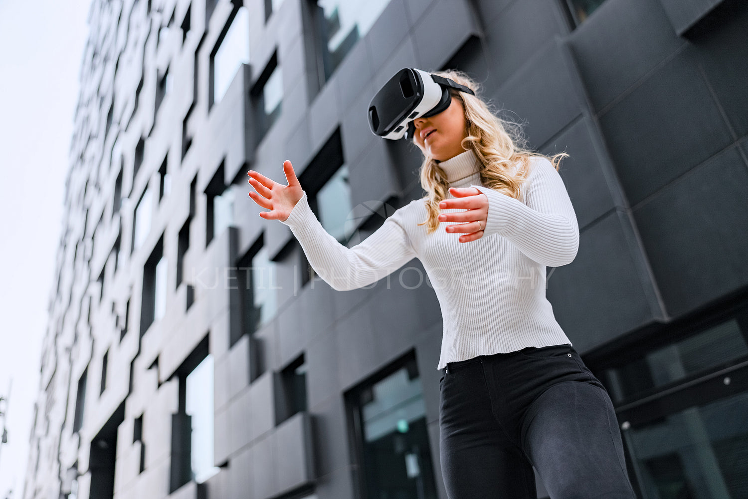 Woman Wearing Virtual Reality Glasses In Front Of Future Looking City Building
