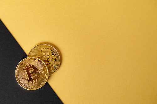 Gold bitcoin cryptocurrency coins on split gold yellow and black backgound
