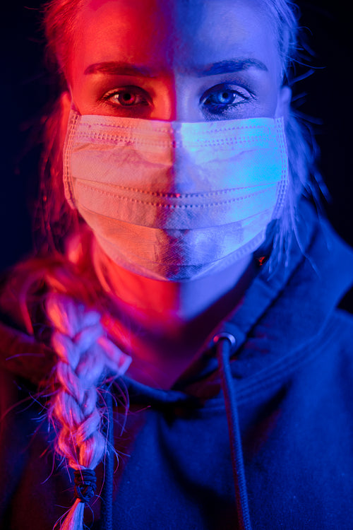 Exhausted or sick woman in protective face mask with multi colored lights