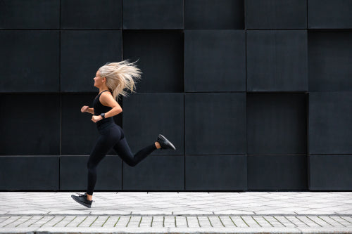 Focused woman running on the city street in modern environment