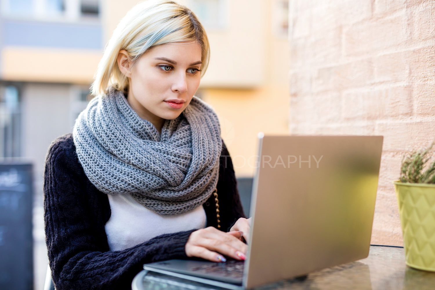 Young Focused Woman Working On Laptop At Outdoor Cafe