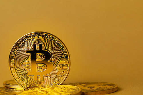 Gold bitcoin cryptocurrency coins on yellow backgound
