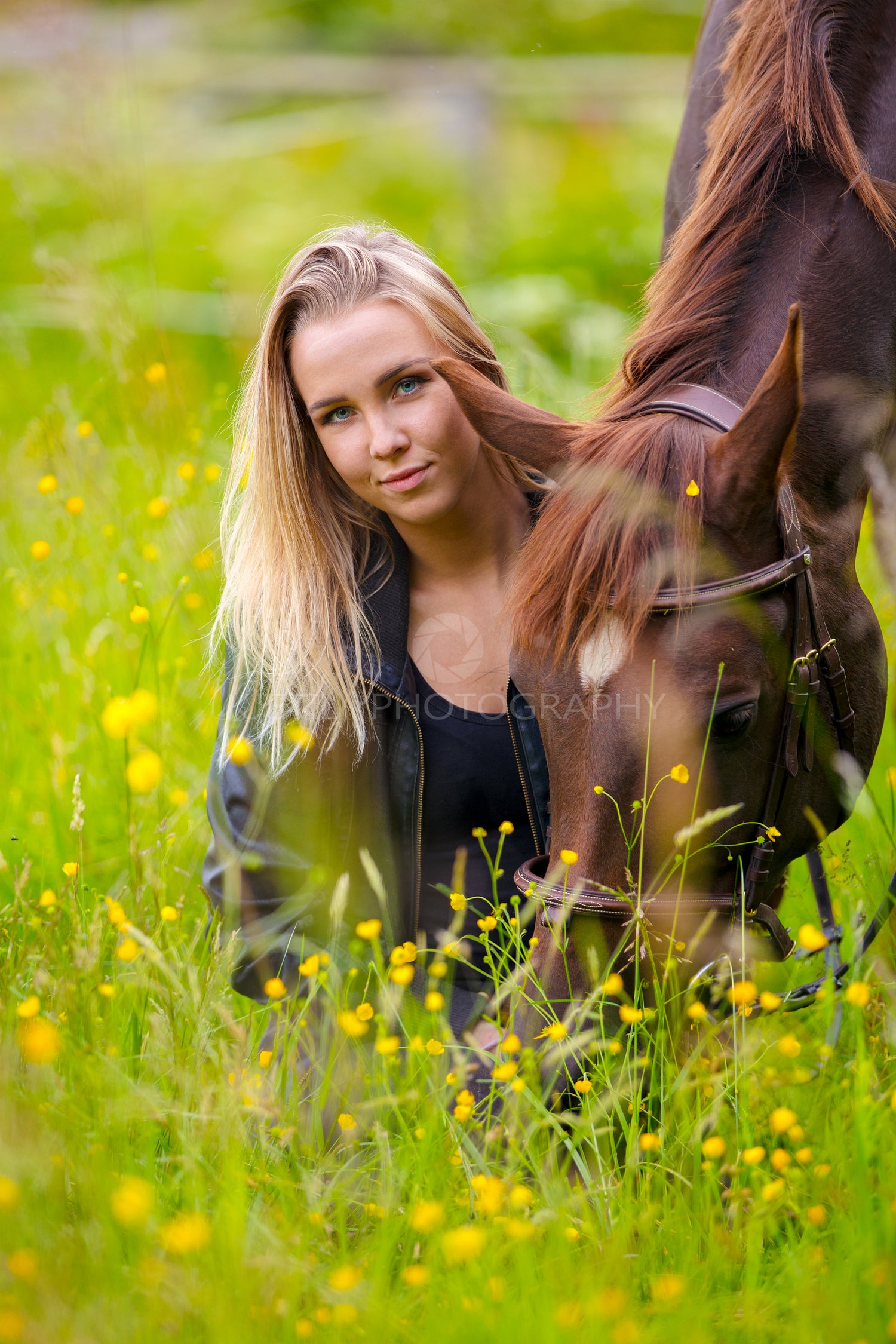 Smiling woman sits in the meadow with her arabian horse