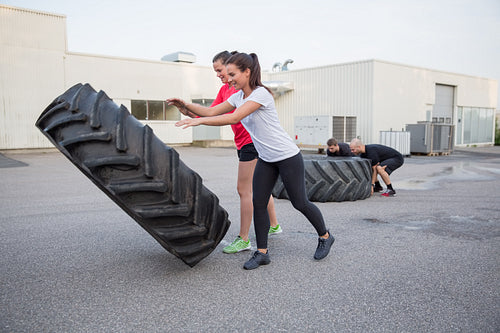 Group of people flipping heavy tires as workout