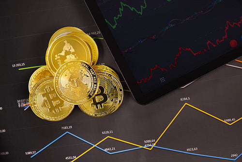 Crypto coins near digital tablet on graph
