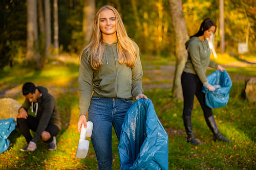 Young female volunteer holding garbage bag at park