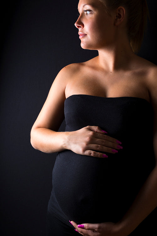 Beautiful pregnant woman stand with hands at the belly