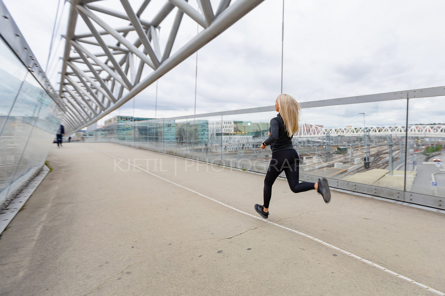 Female runner in black workout outfit in modern city environment