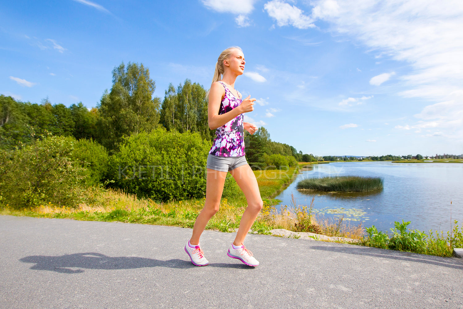 Sporty young woman runs on road along the water