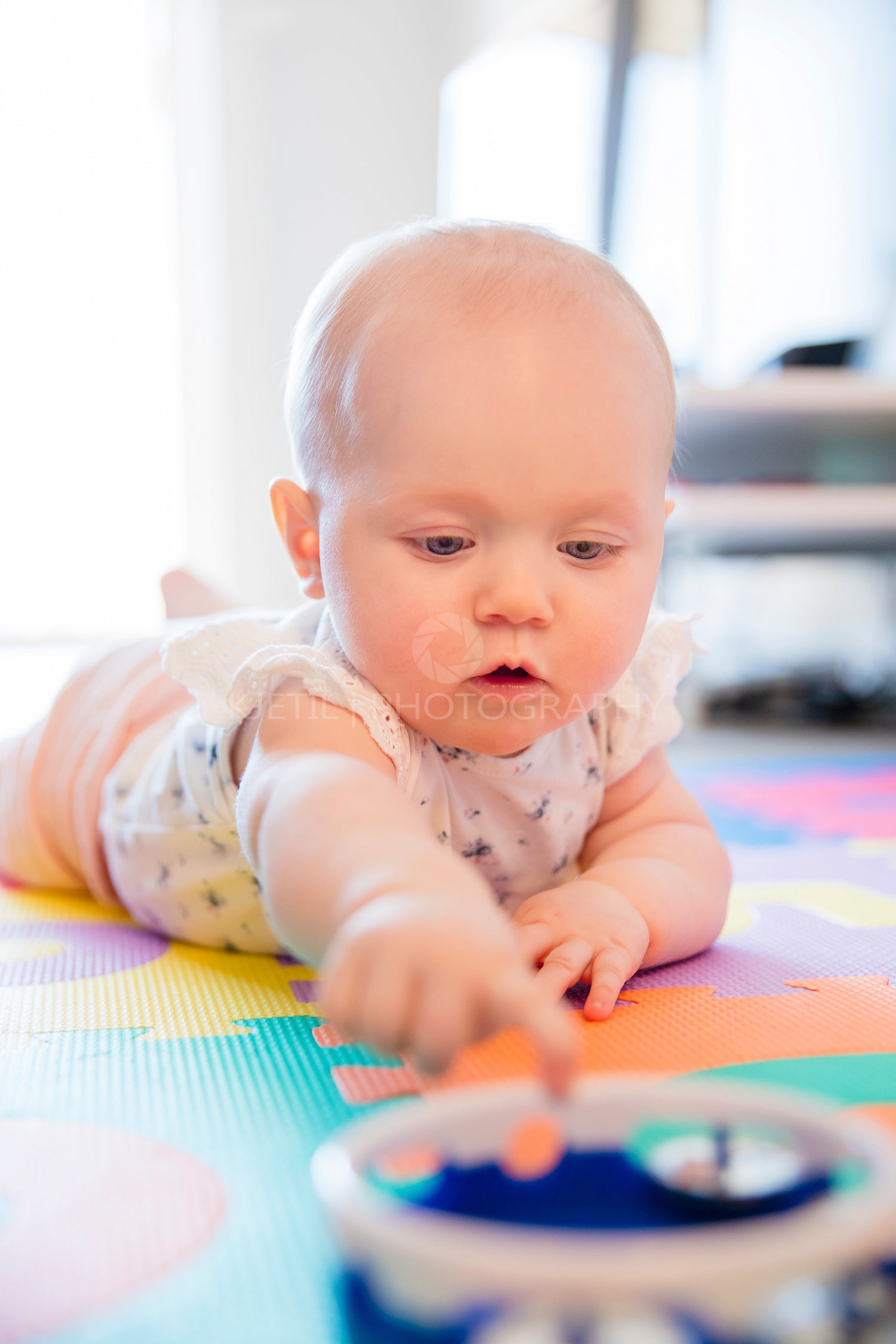 Baby girl with blue eyes playing on mat at floor
