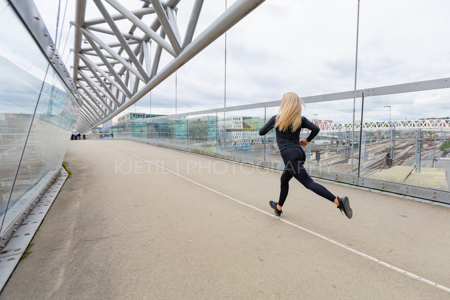 Female runner during fast running exercise in modern city at cloudy day.
