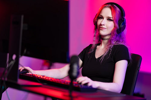 Focused professional e-sport gamer girl streaming and plays online video game on PC