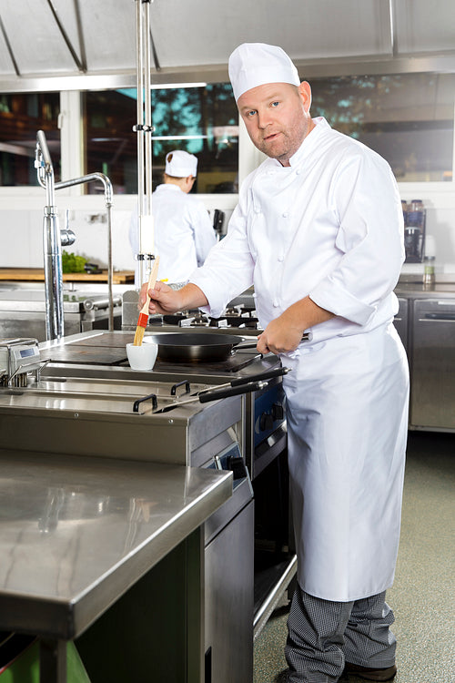 Chef using brush to prepare a dish in the kitchen