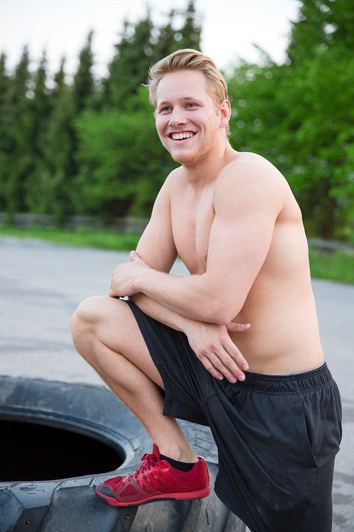 Smiling man with bare upper body rests outdoor