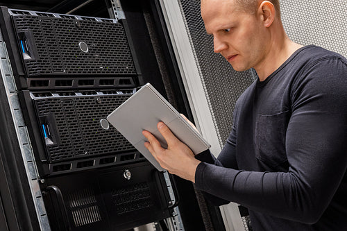 Male Technician Holding Digital Tablet Analyzing Servers in Datacenter