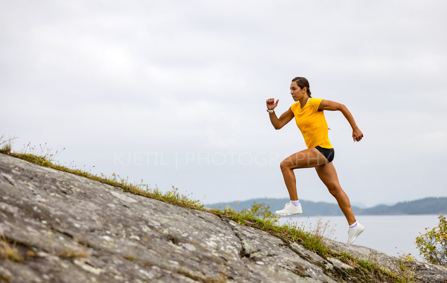Side view of fitness woman doing high-intensity running on mountainside by the sea