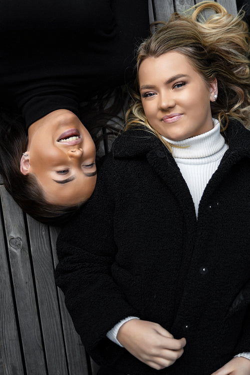 Smiling Friends Lying On Bench Together in City