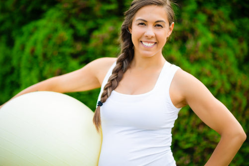 Smiling Young Pregnant Woman Holding Fitness Ball In Park