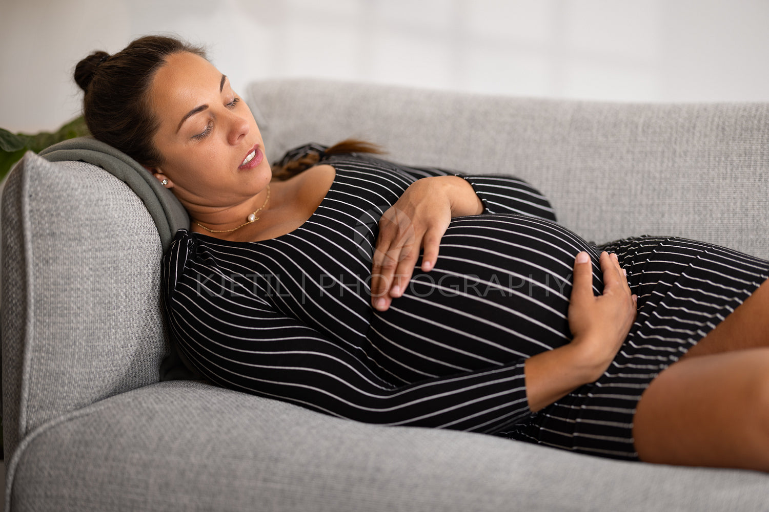 Exhausted and Tired Pregnant Woman in Striped Dress lying in a sofa
