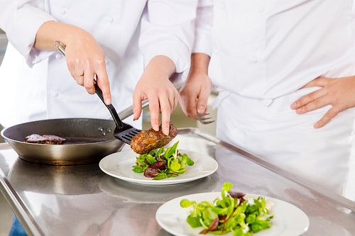 Professional chefs prepares steak dishes at restaurant