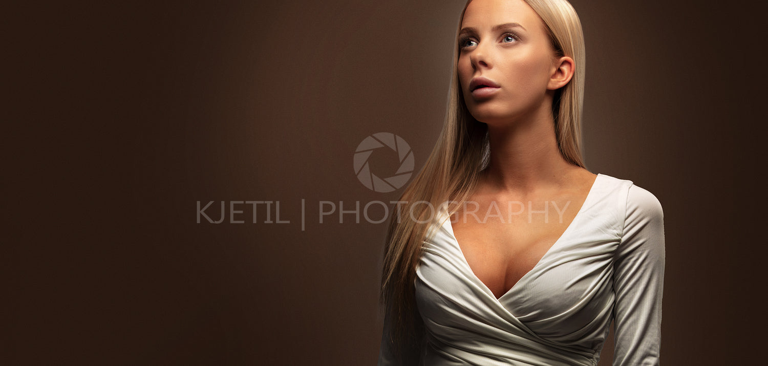 Wide studio portrait of a beautiful woman in white dress looking away