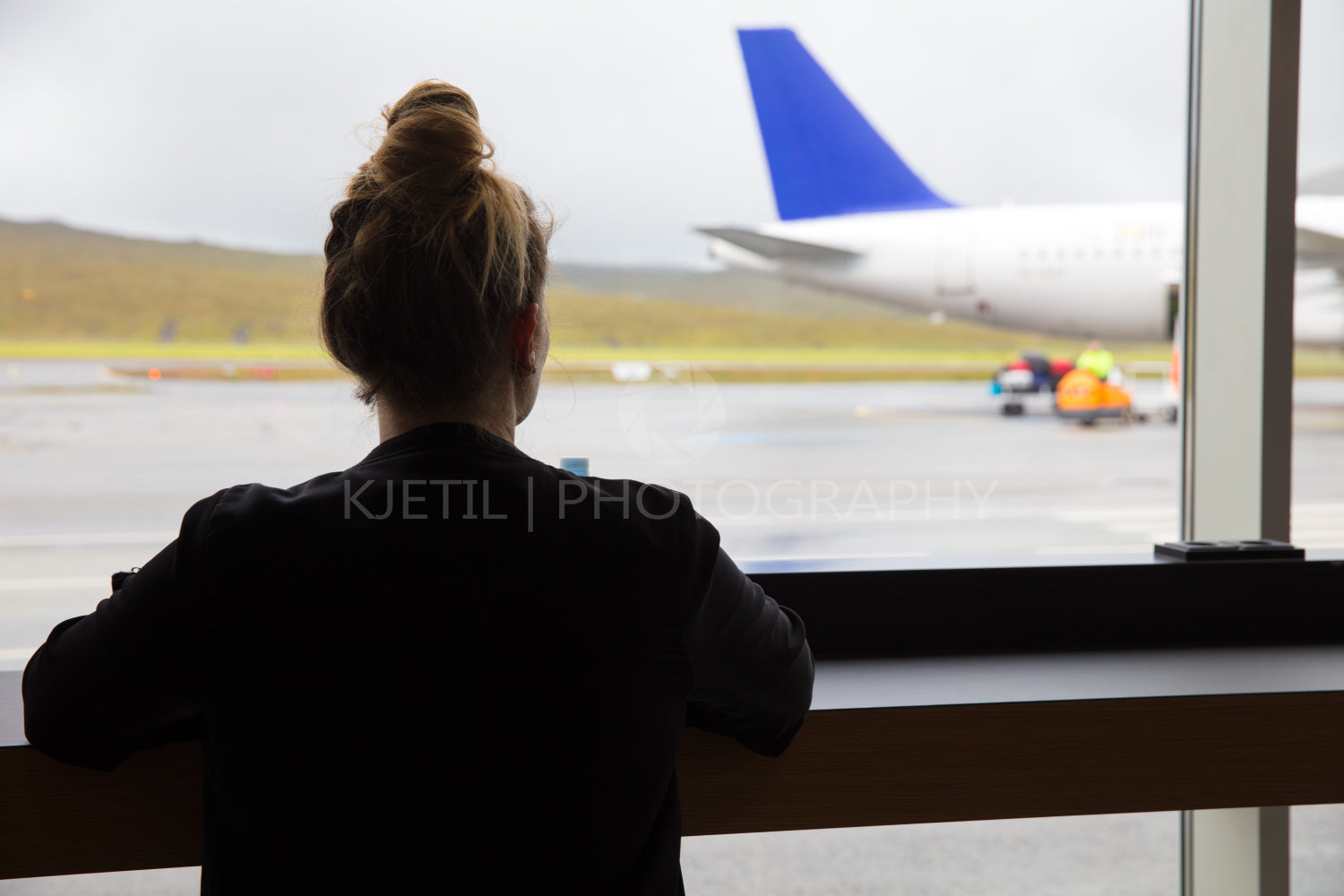 Woman Looking At Airplane Through Window At Airport