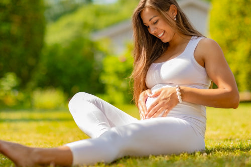 Smiling pregnant woman forming a heart on the belly with her hands