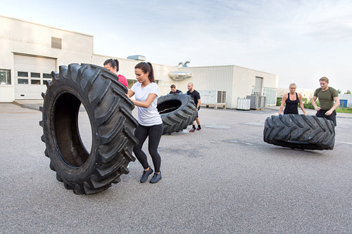 Fitness team flipping heavy tires as workout