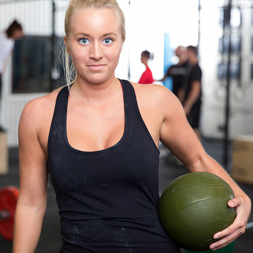 Smiling young woman with slam ball at gym center