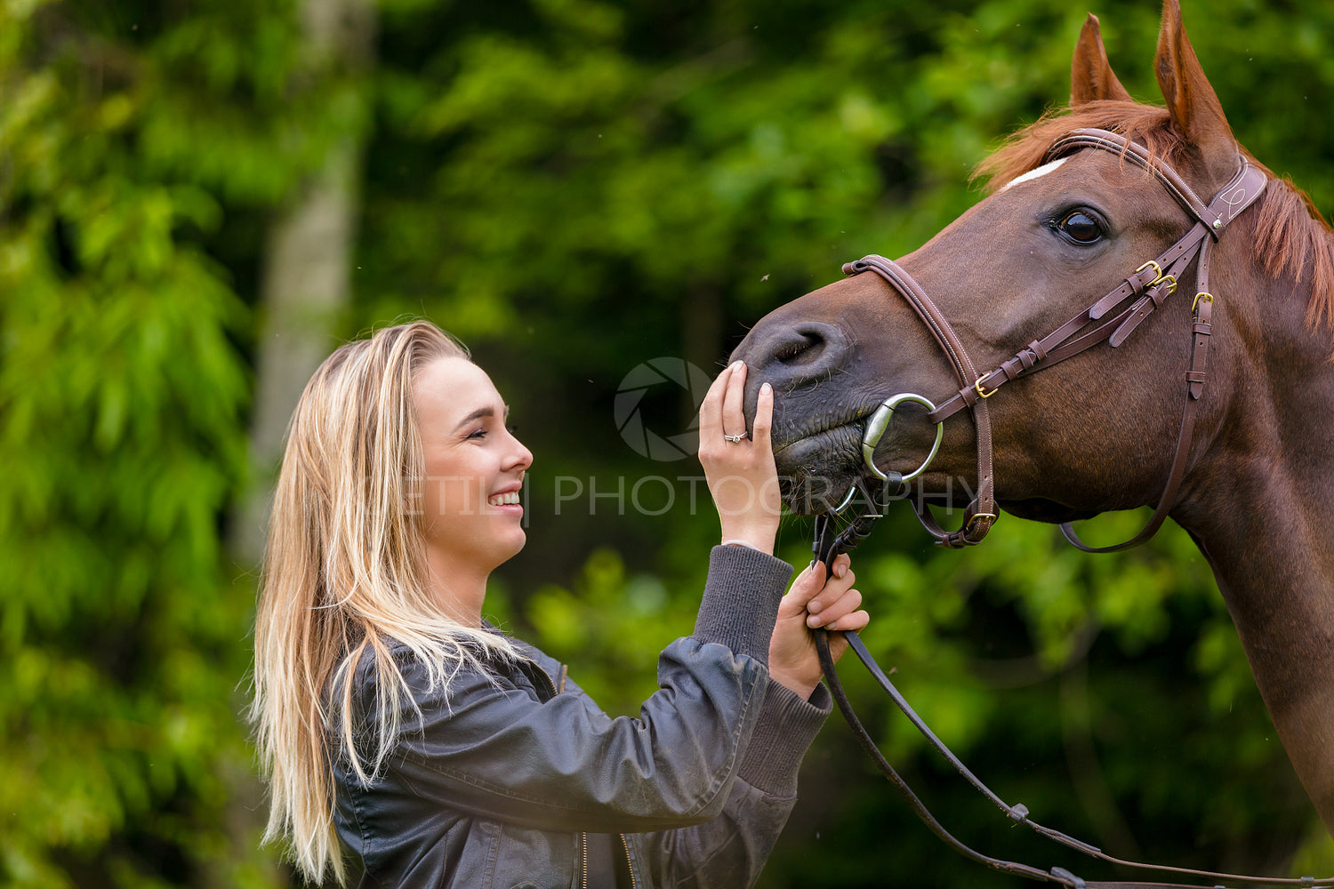 Close-up of smiling woman feeding her arabian horse with snacks