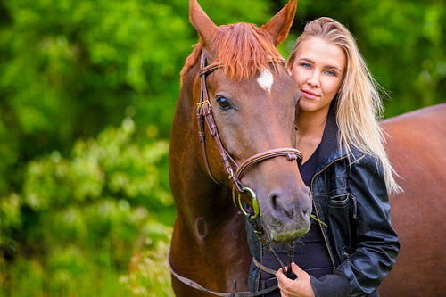 Beautiful smiling woman with her arabian horse in the field