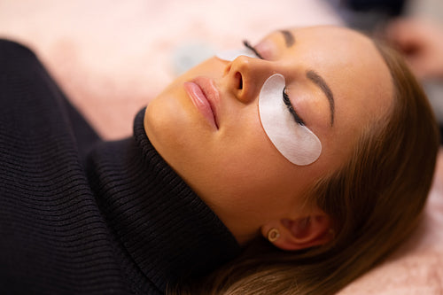 Woman With Cotton Pads Lying During Eyelash Extension Treatment
