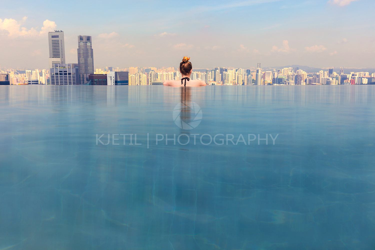 Woman Looking At Cityscape While Relaxing In Infinity Pool