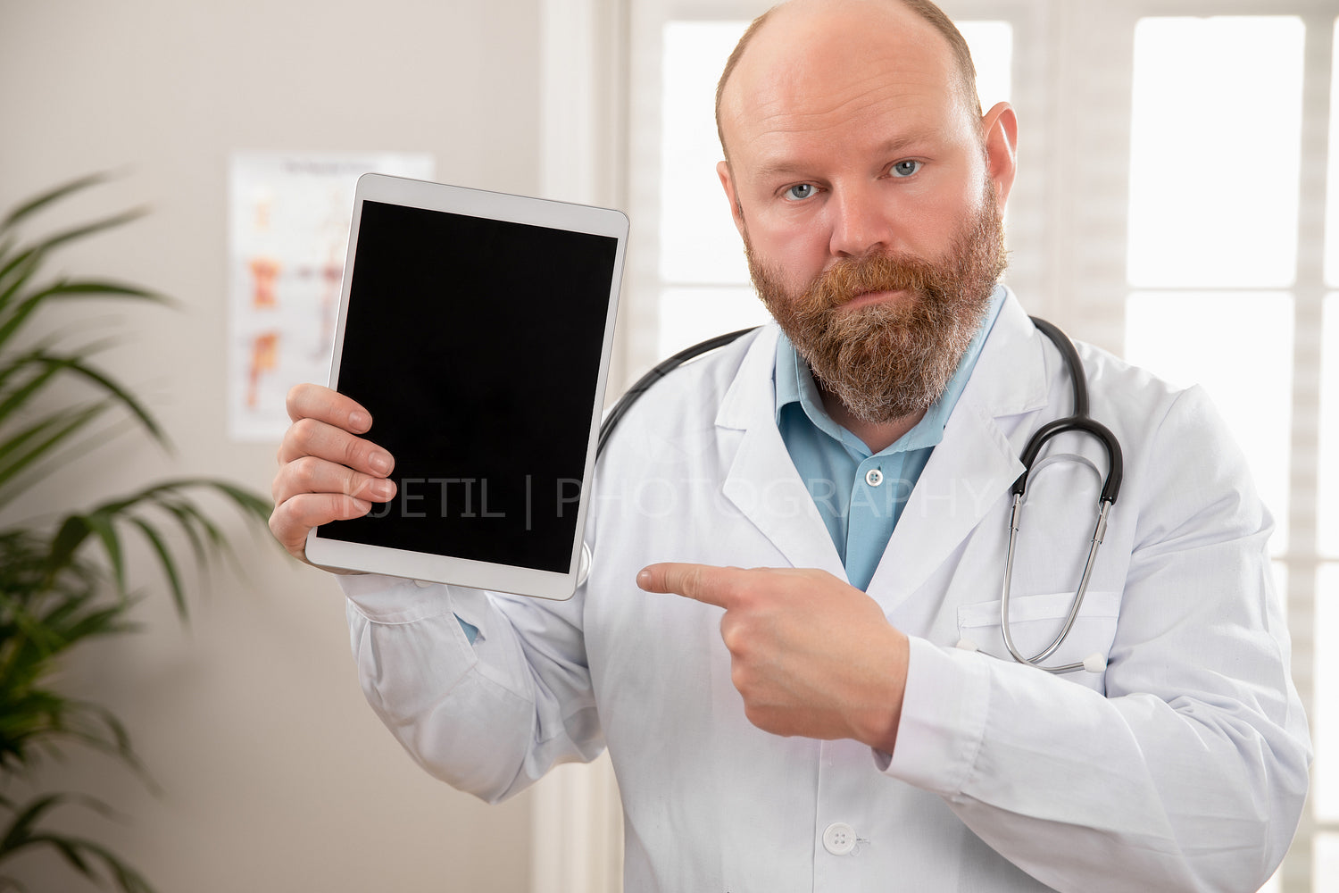 Serious adult male doctor showing a digital image or report on a tablet