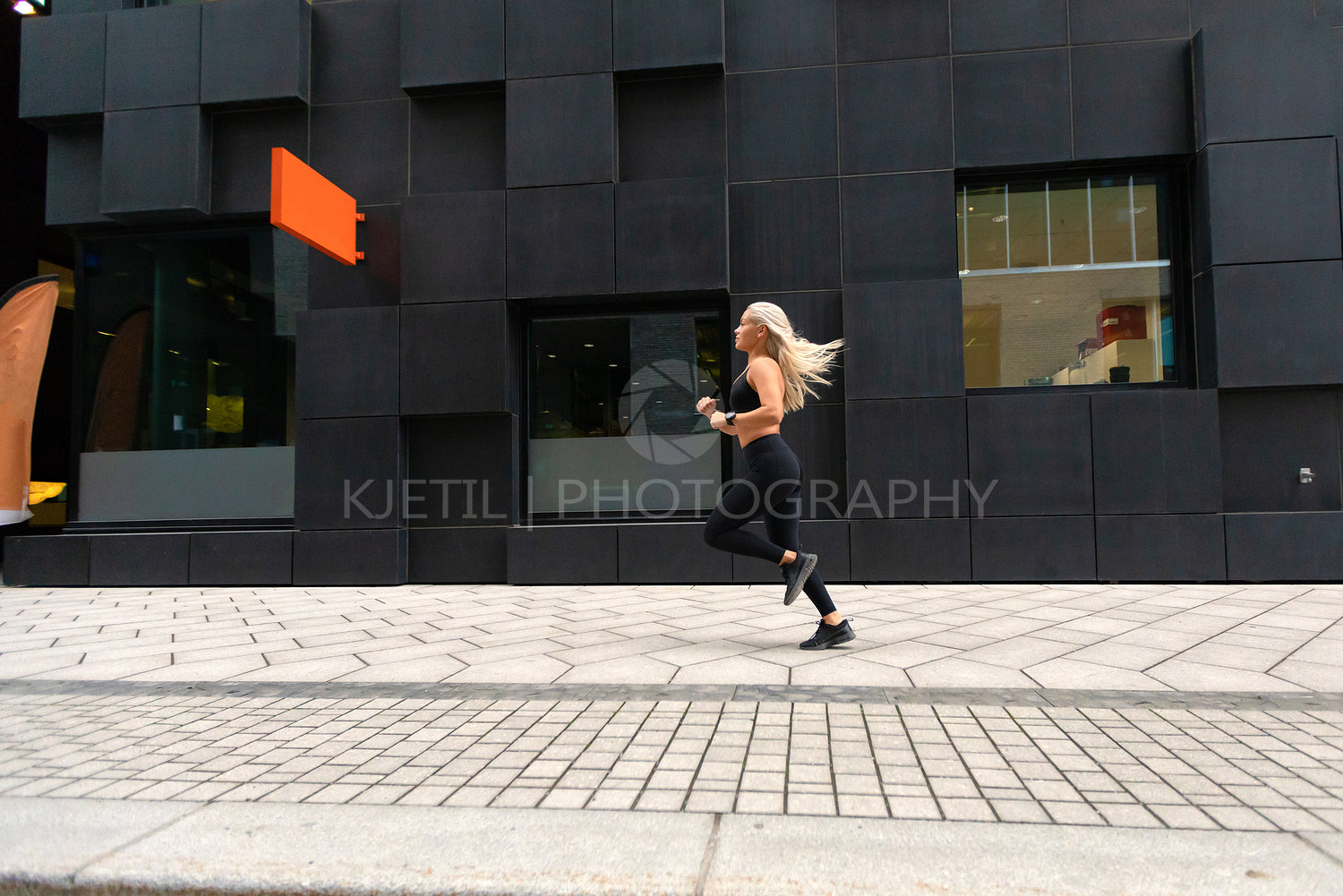 Side view of sporty young woman runner in minimalist urban environment