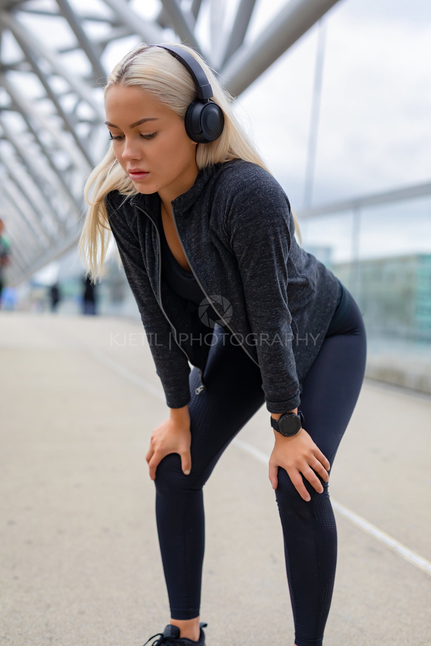 Exhausted Female Runner Resting With Hands On Knees After Workout