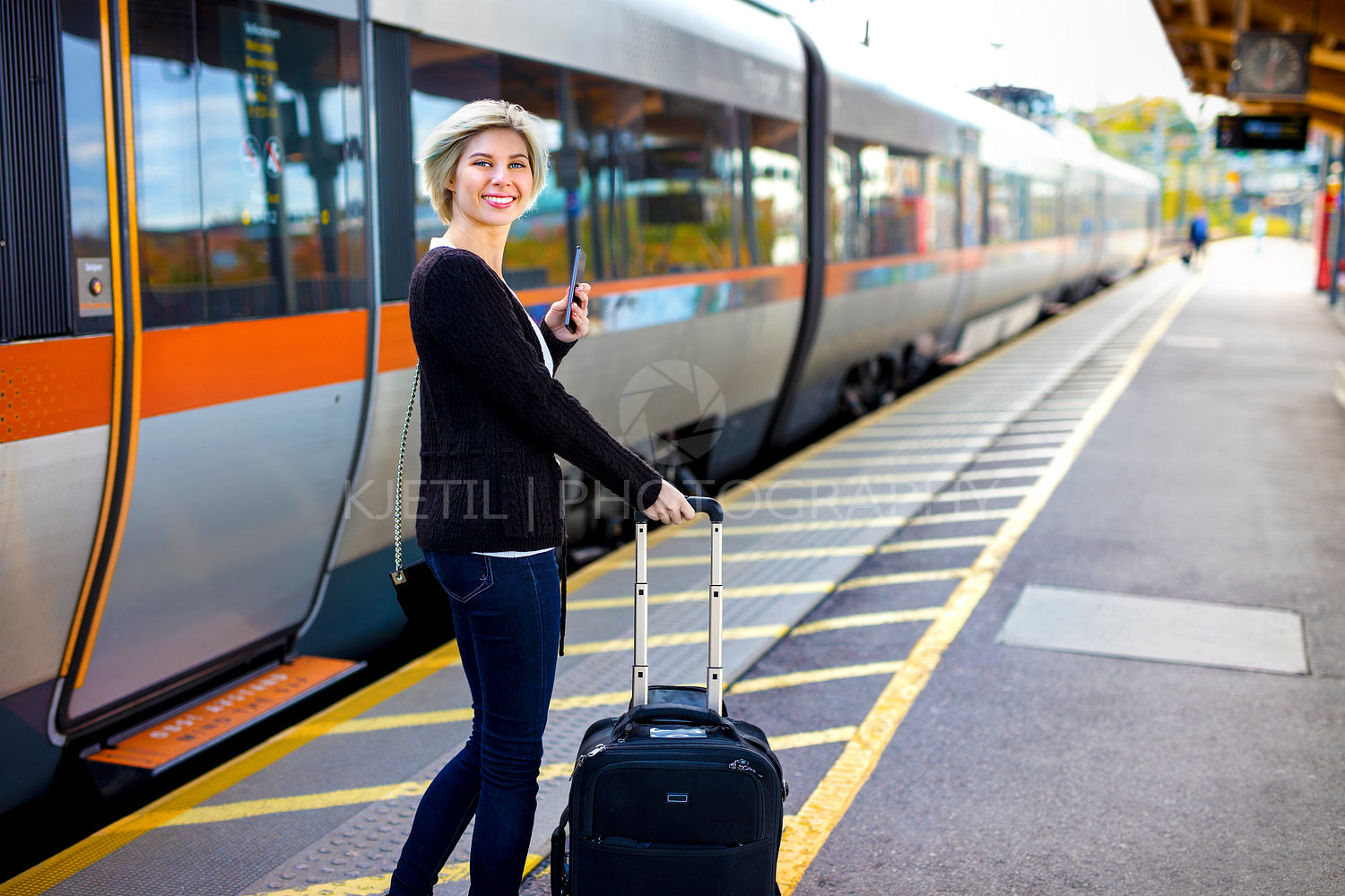 Happy Woman With Mobile Phone And Luggage At Train Station