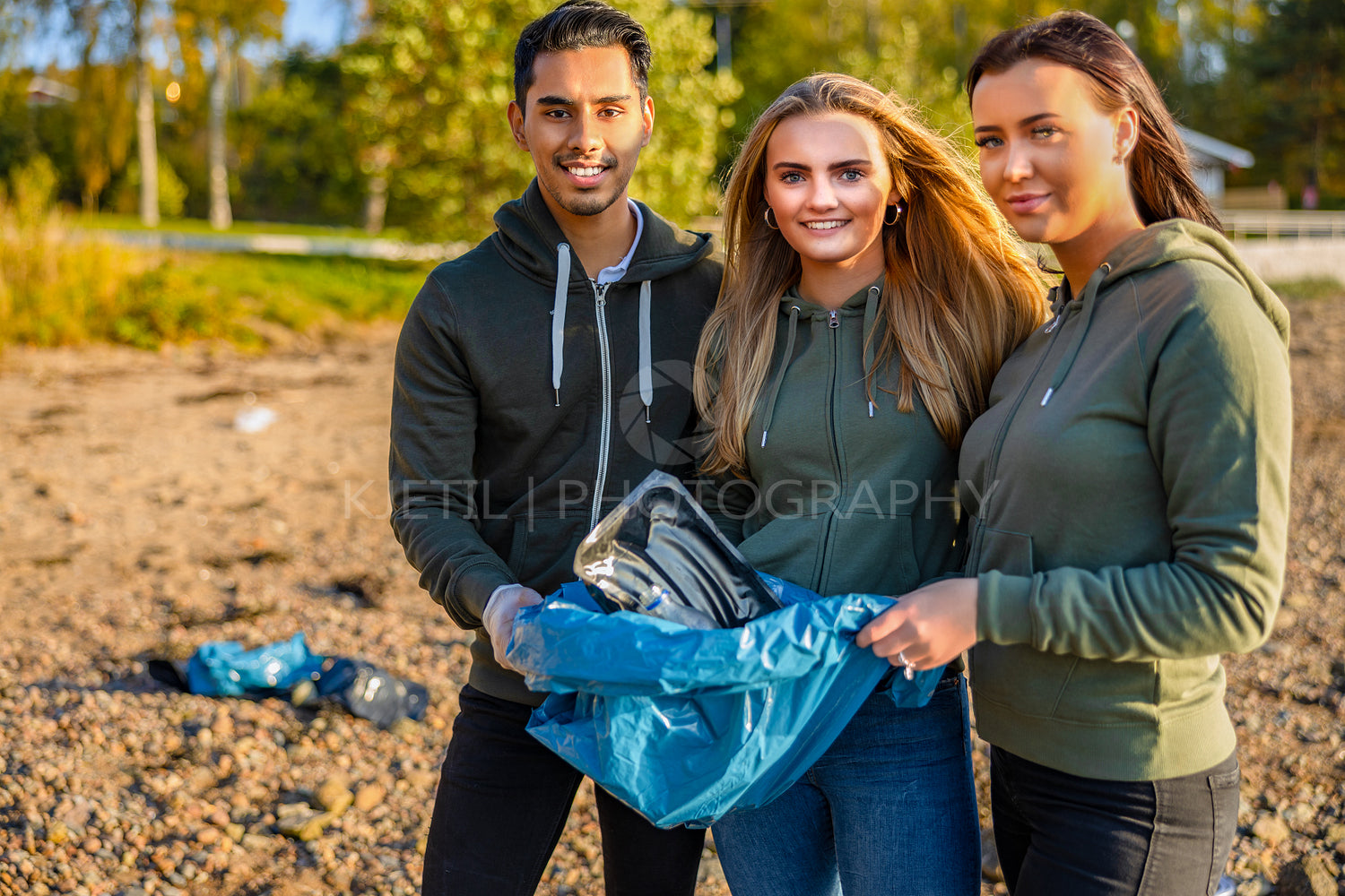 Smiling volunteers holding garbage bag at beach