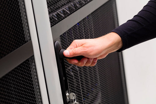 IT engineer opens door to server rack in datacenter