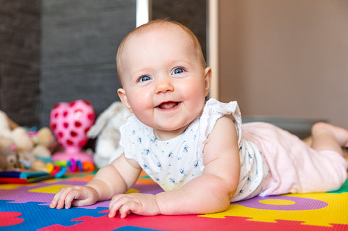 Smiling baby girl with blue eyes playing on floor