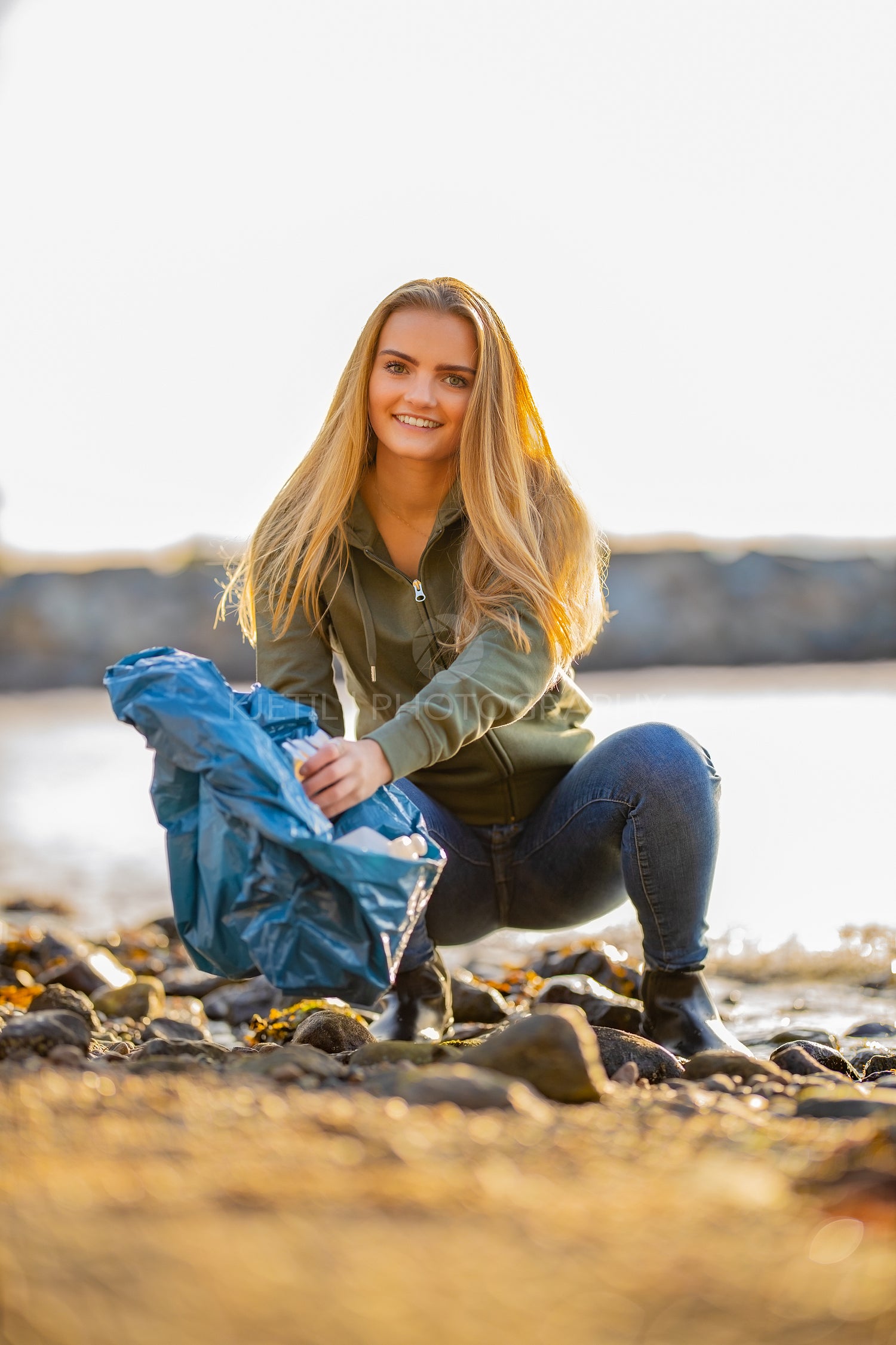 Young volunteer woman picking up aerosol and garbage can at beach