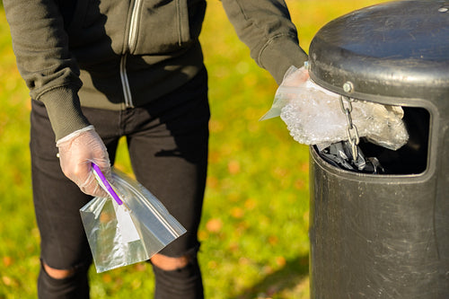 Volunteer putting plastic trash in garbage bin at park