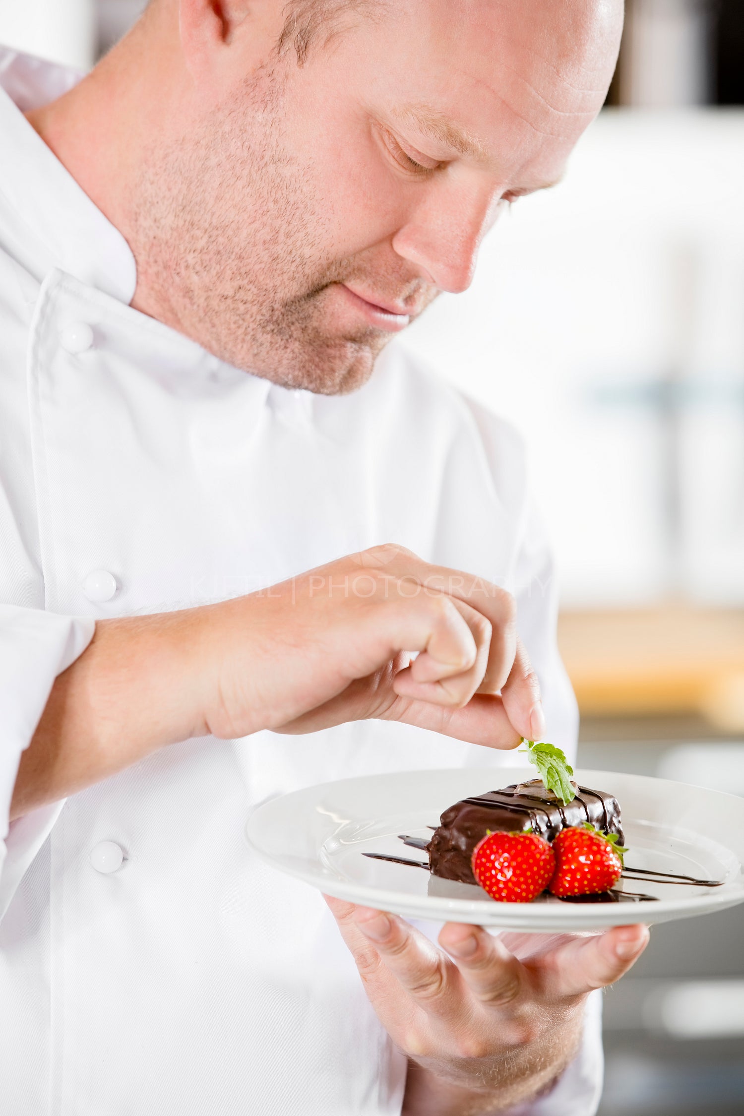 Close-up of chef adding lemon leaf at chocolate cake