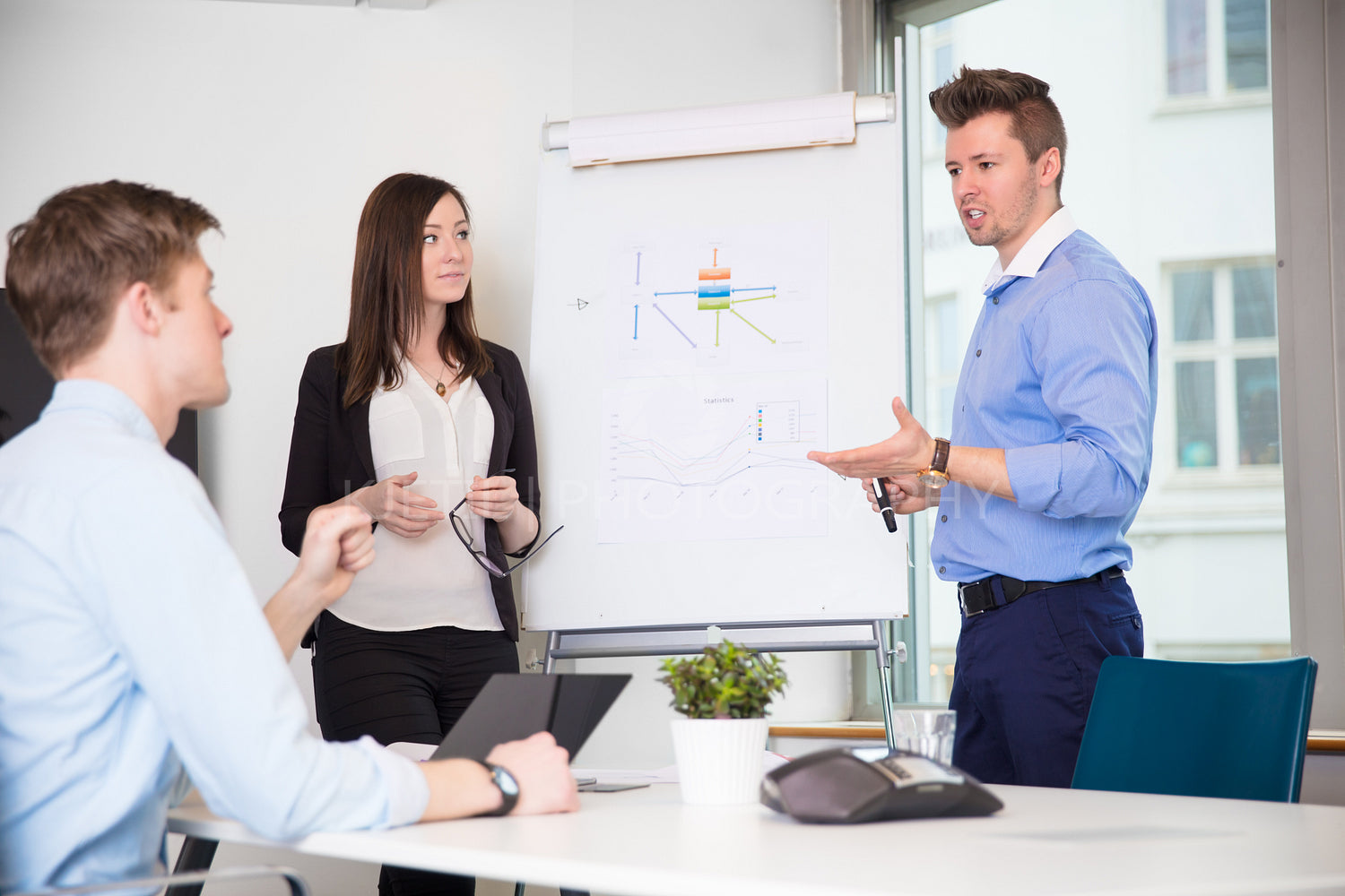 Male Professional Explaining Chart To Coworkers In Office
