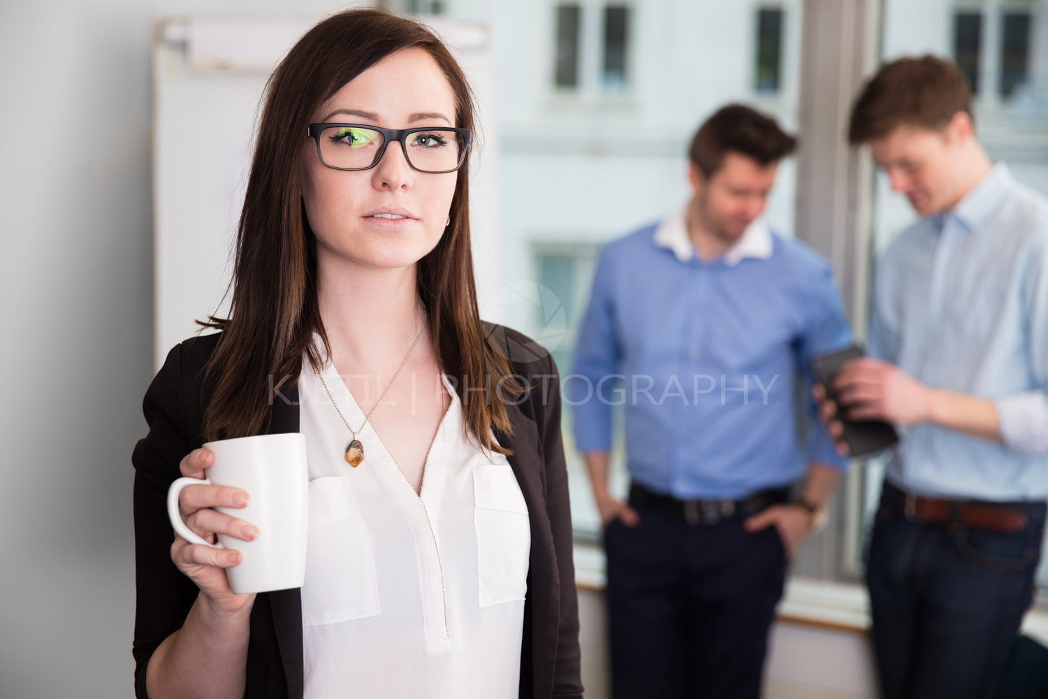 Businesswoman Holding Coffee Mug While Colleagues Discussing In