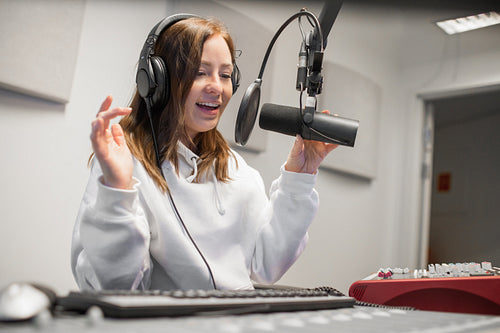 Female Host Communicating On Microphone In Radio Studio