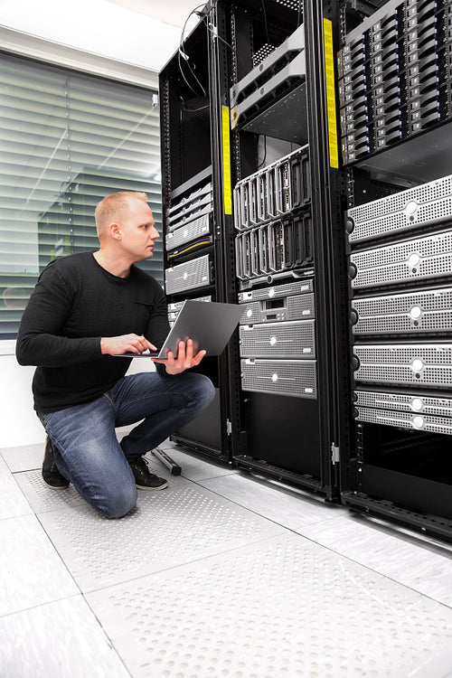 Male Consultant Using Laptop While Monitoring Servers In Datacen
